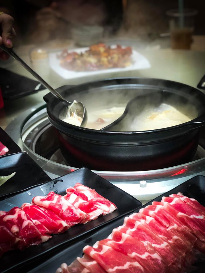 at hotpot restaurant with two soup bases and meat slices