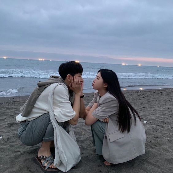 Asian couple squatting facing each other in the beach