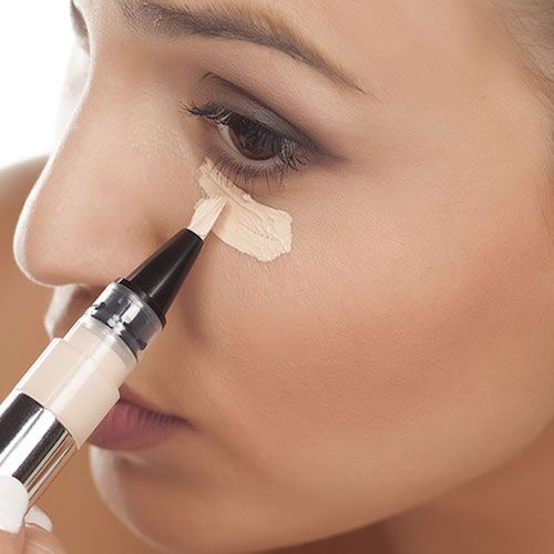 Girl applying concealer on under eyes