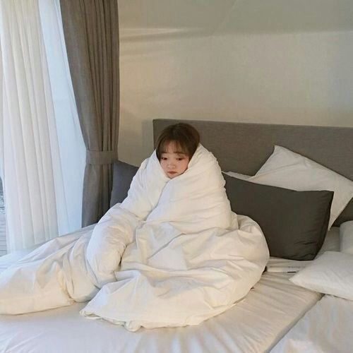 asian girl wrapped up in blanket on bed