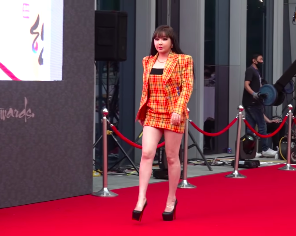 Park Bom wearing yellow checkered two-piece outfit with a blazer and mini skirt