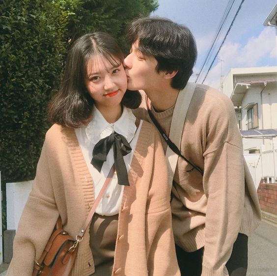 Asian couple wearing matching outfits kissing on cheek