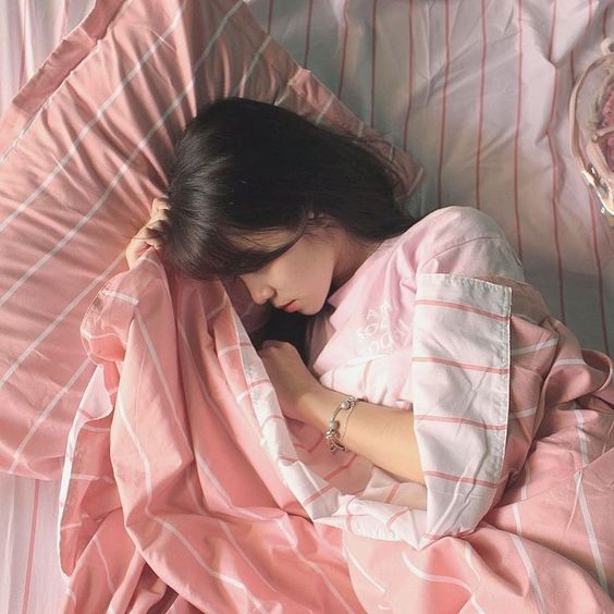 asian girl sleeping on bedc with pink and grey bedsheets