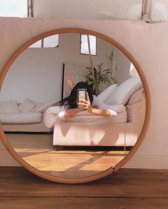 asian woman lying on bed and taking a mirror selfie