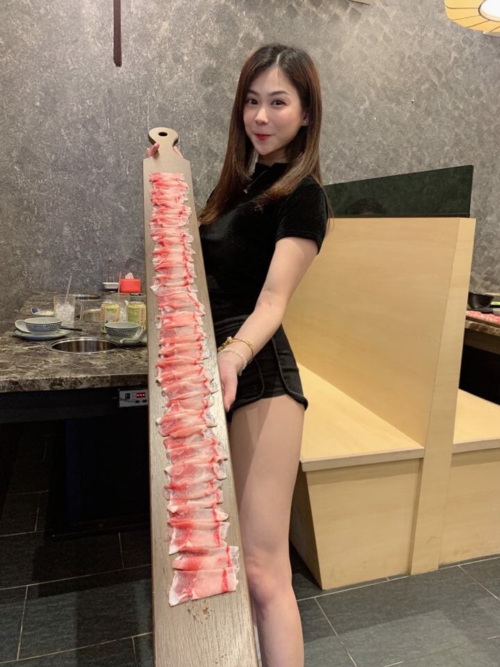 asian woman holding pork slices at at hotpot restaurant
