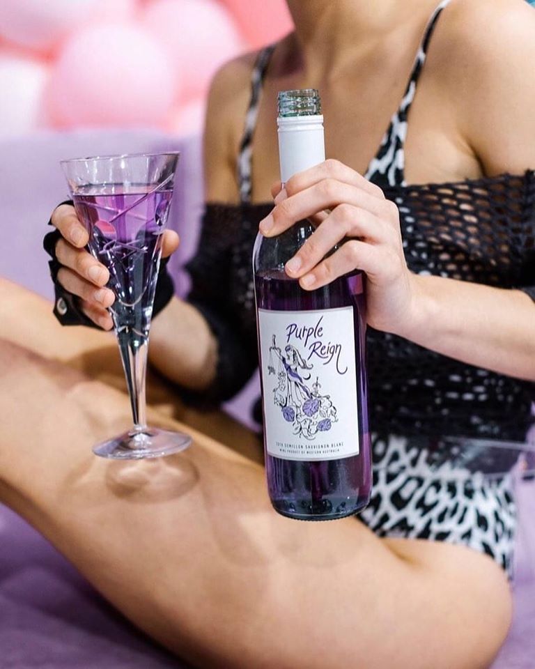 woman holding Purple Reign wine bottle and in a cocktail glass