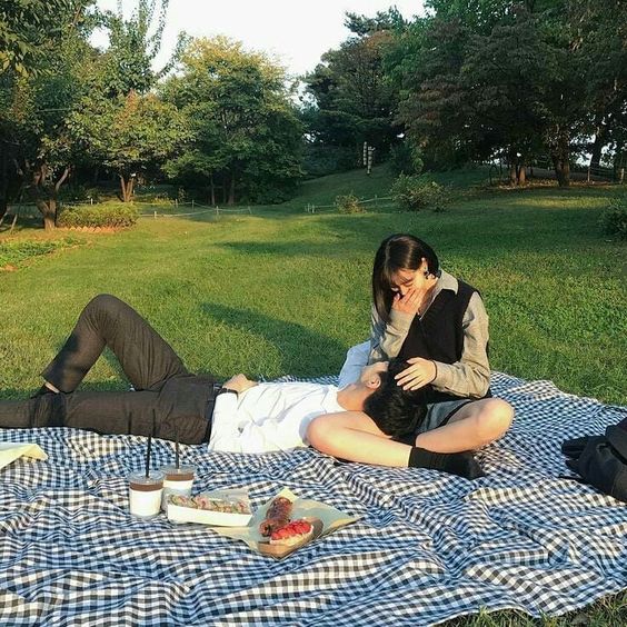 asian couple having a picnic boy lying down on girl's lap