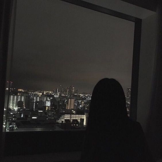 silhouette of woman against cityscape at night