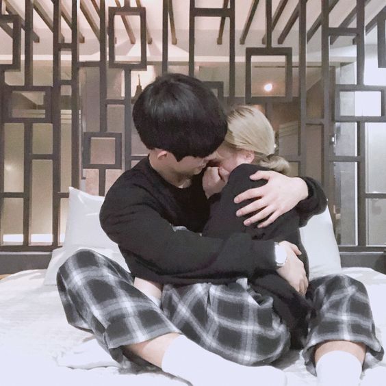 asian couple wearing matching pyjamas and cuddling in bed