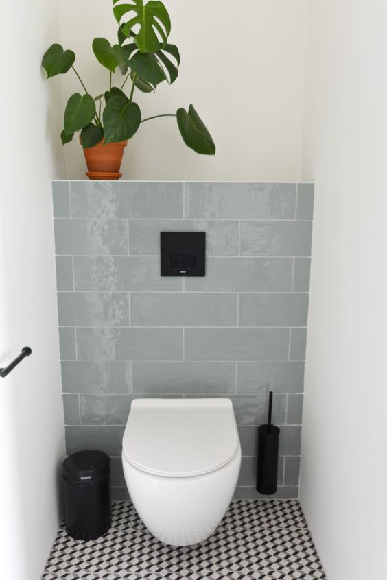 white bathroom with blue tiles, toilet and plant