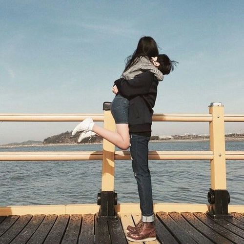 asian guy lifting girl up at the pier by the sea