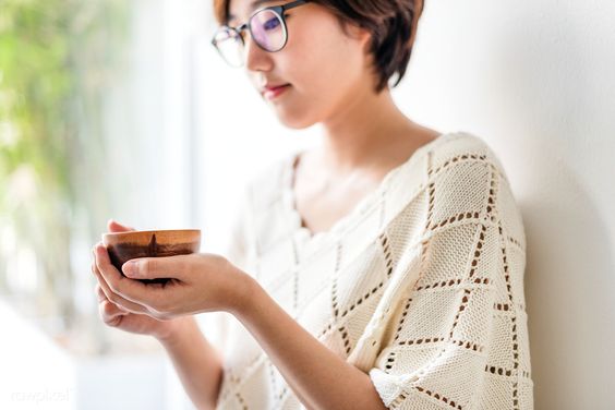 asian woman drinking a cup of green tea