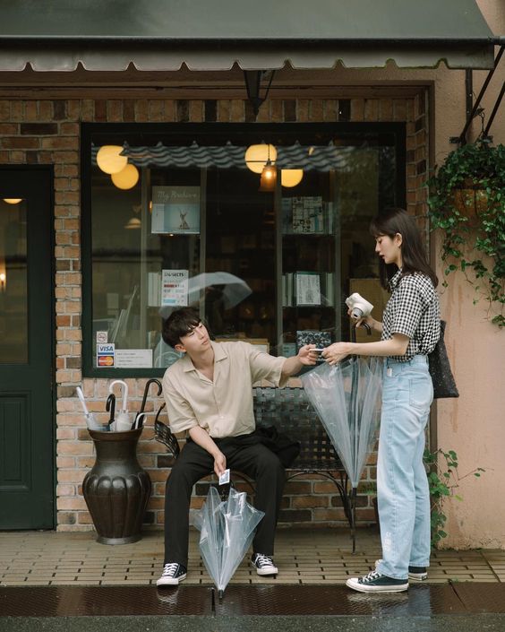 asian couple holding clear umbrellas in front of a shop