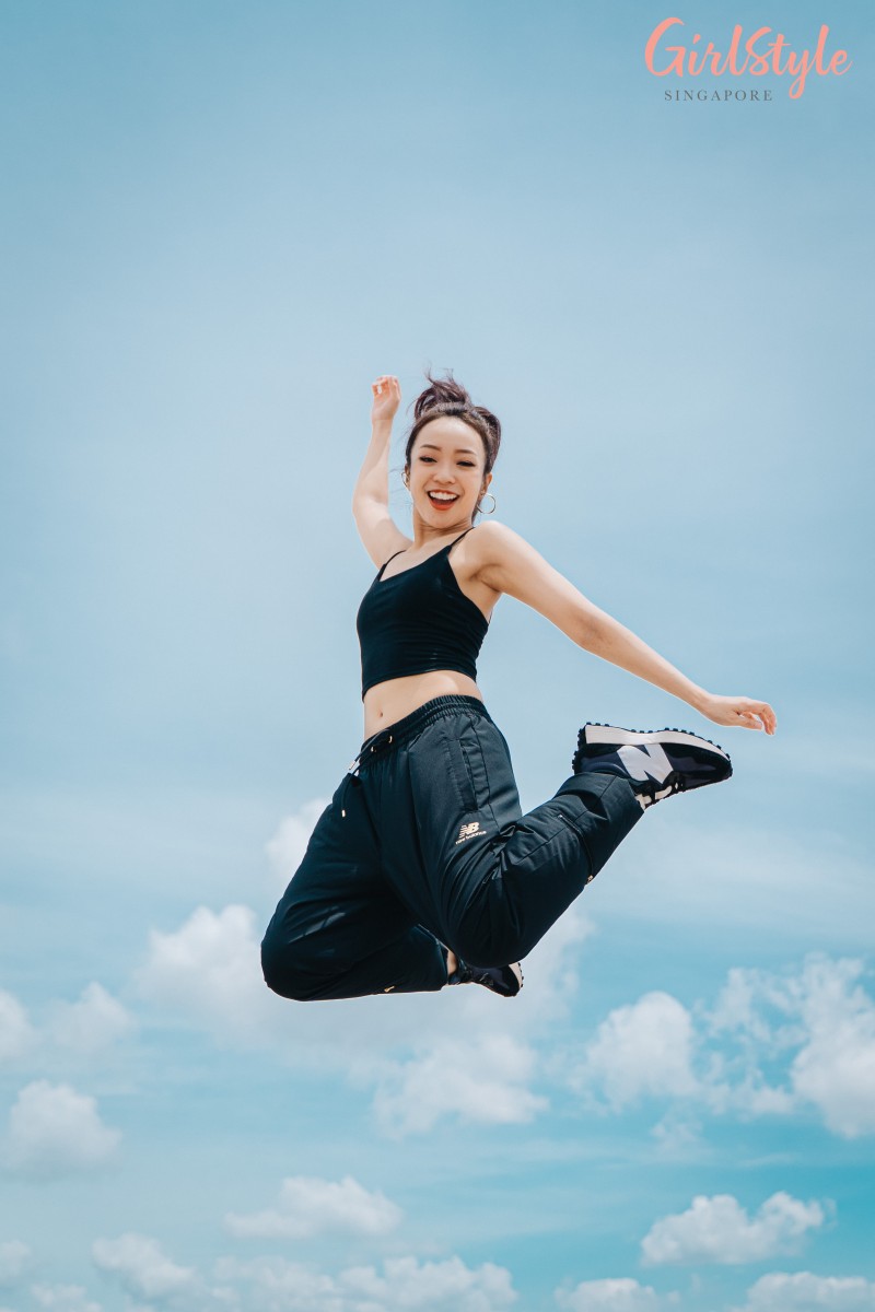 asian woman doing jumpshot wearing black crop top and New Balance Athletics Podium Wind Sweatpants and 327 sneakers