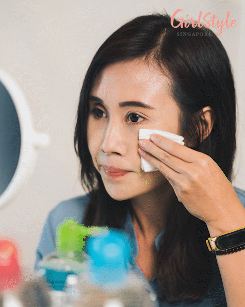 asian woman cleansing her face with micellar water on a cotton pad
