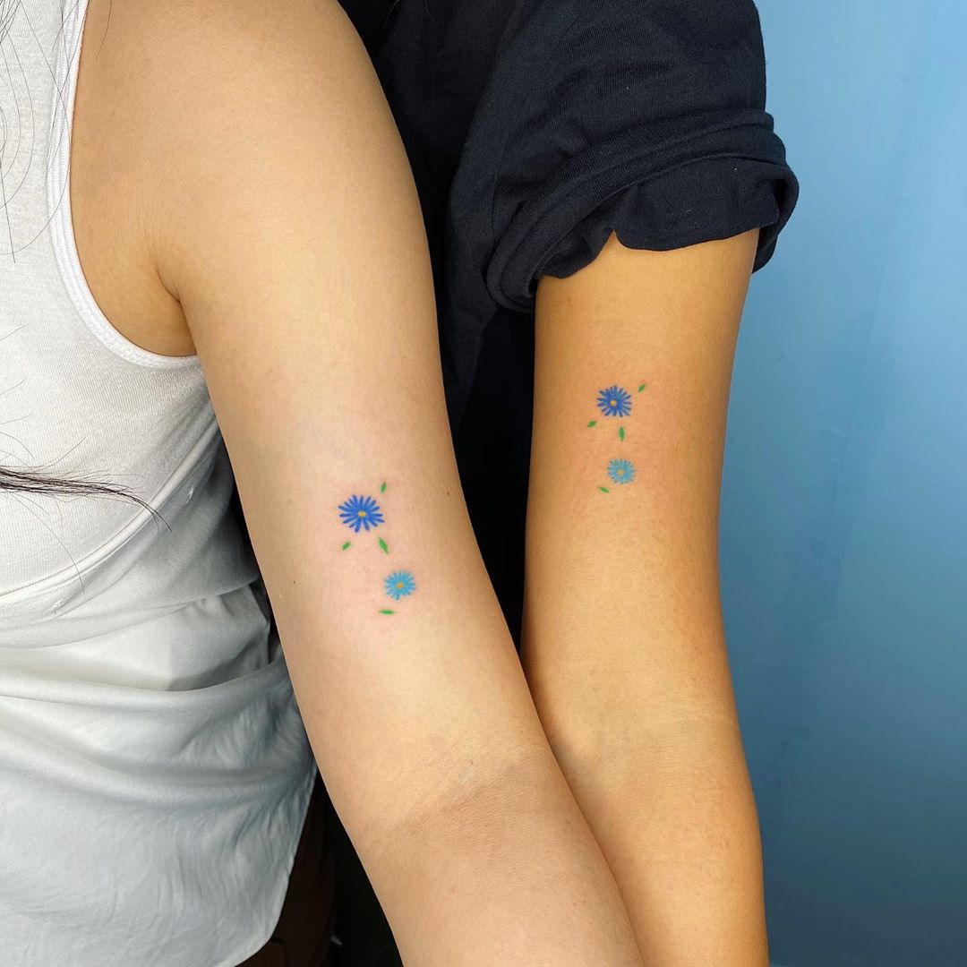 small blue flower hand poked tattoo on arm