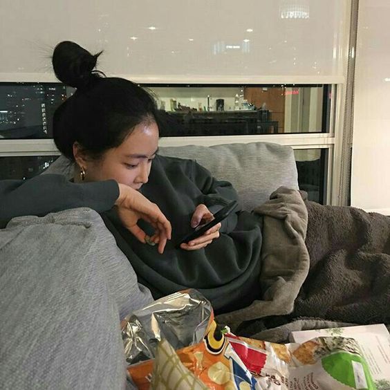 asian girl eating chips on sofa
