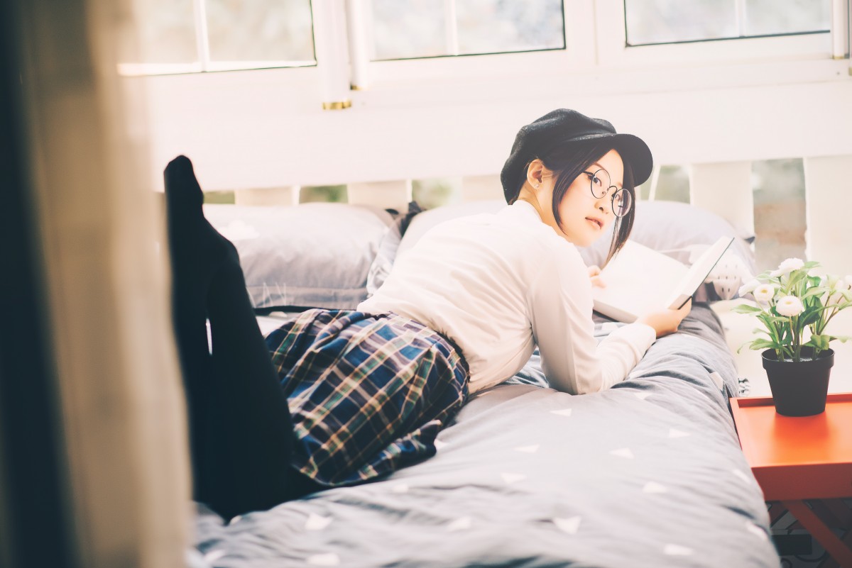 asian girl lying on bed with a book