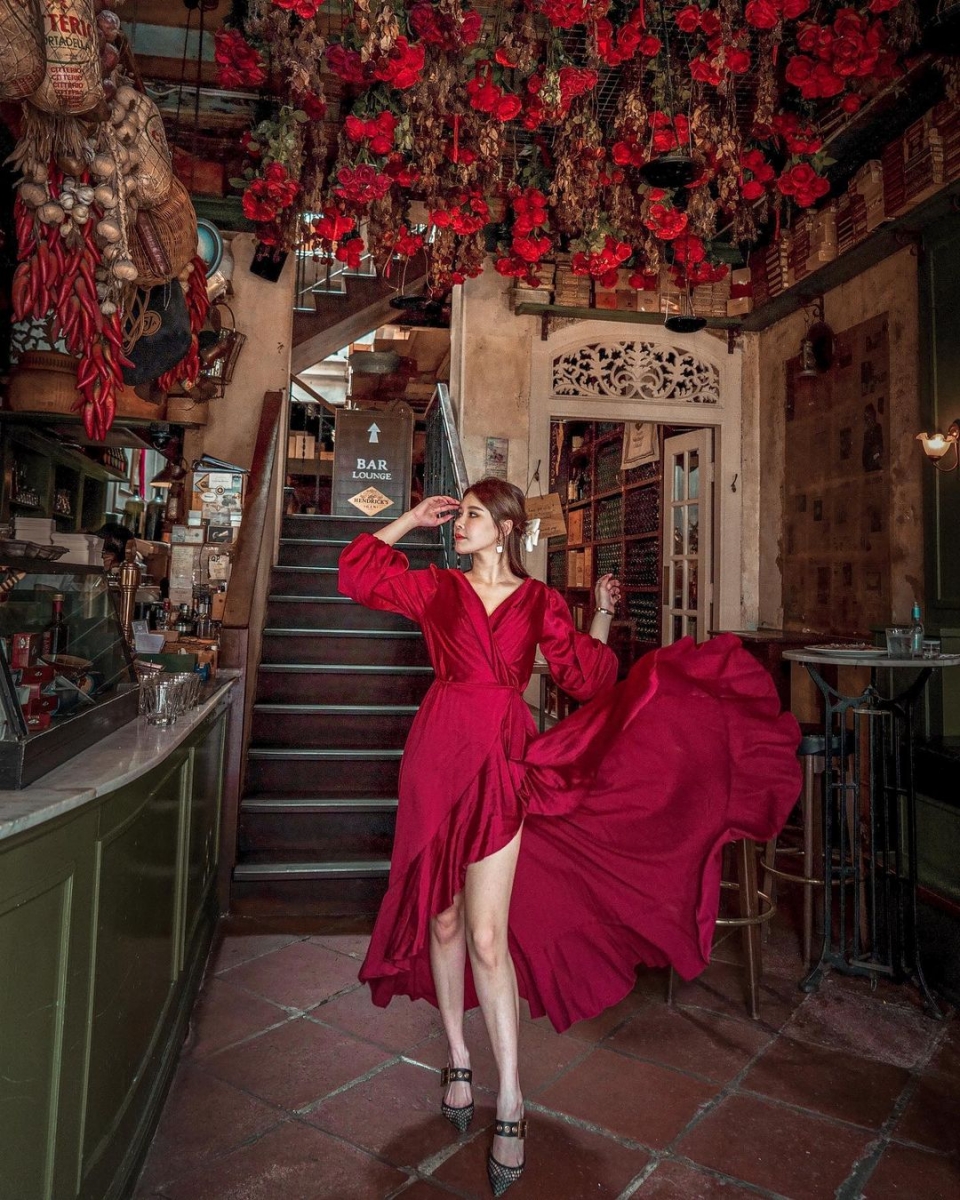 girl wearing red dress in que pasa bar in singapore with ceiling of roses