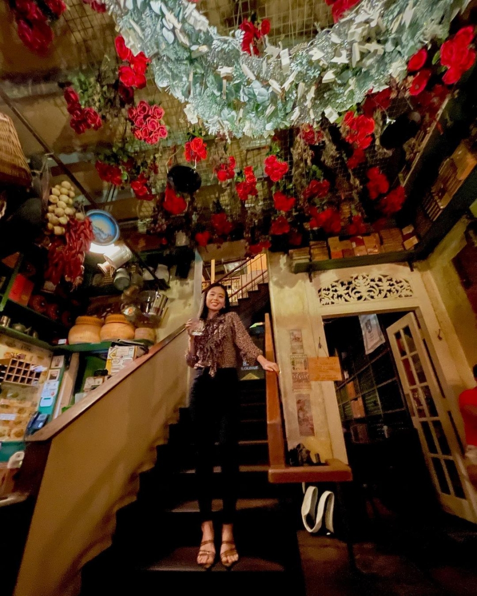 girl standing on stairs with ceiling of roses at que pasa bar in singapore