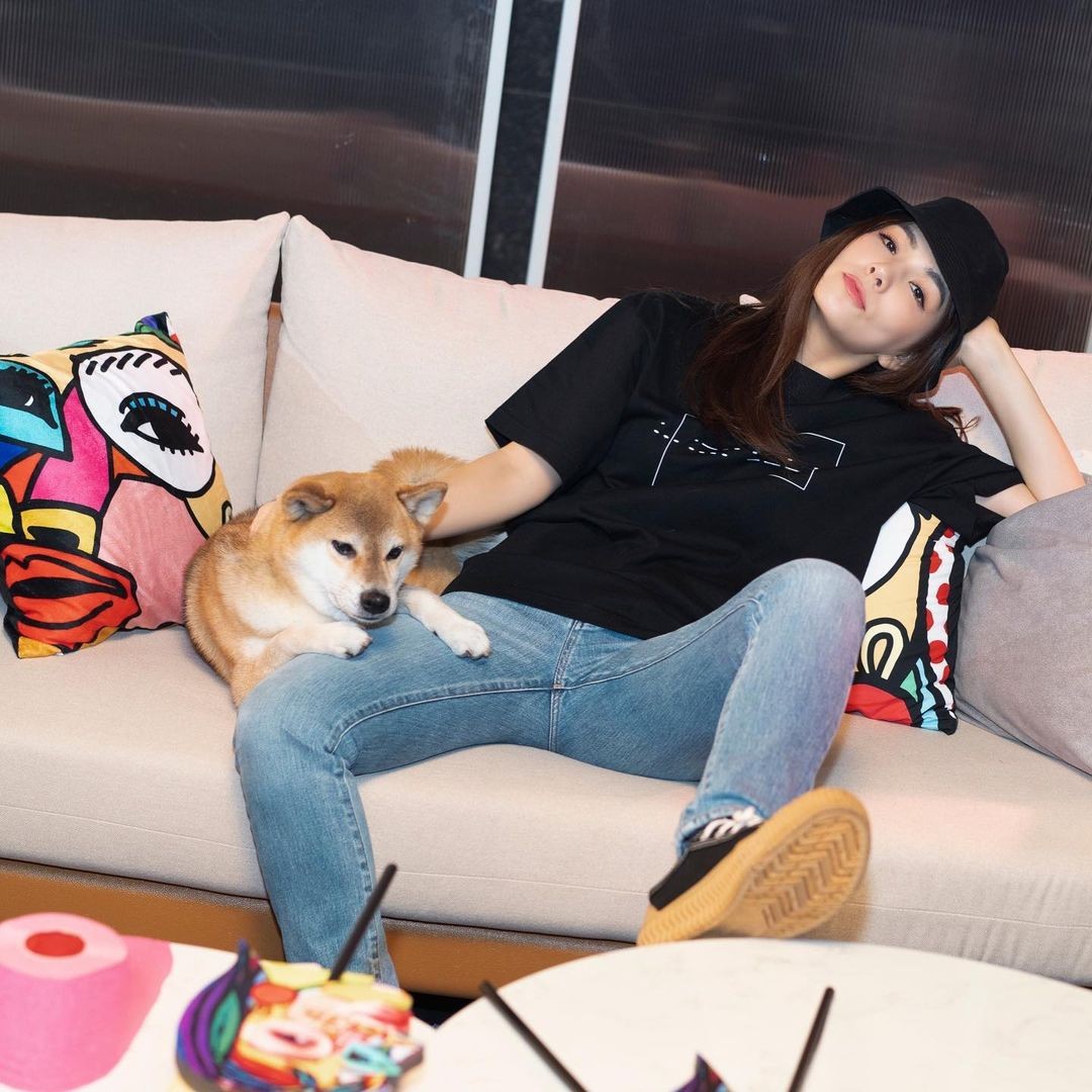 ella chen wearing black tshirt and jeans on sofa