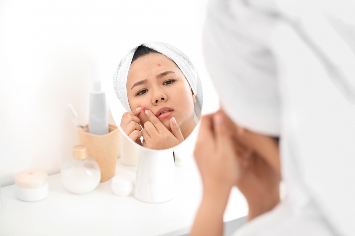 Lady squeezing pimple in the mirror