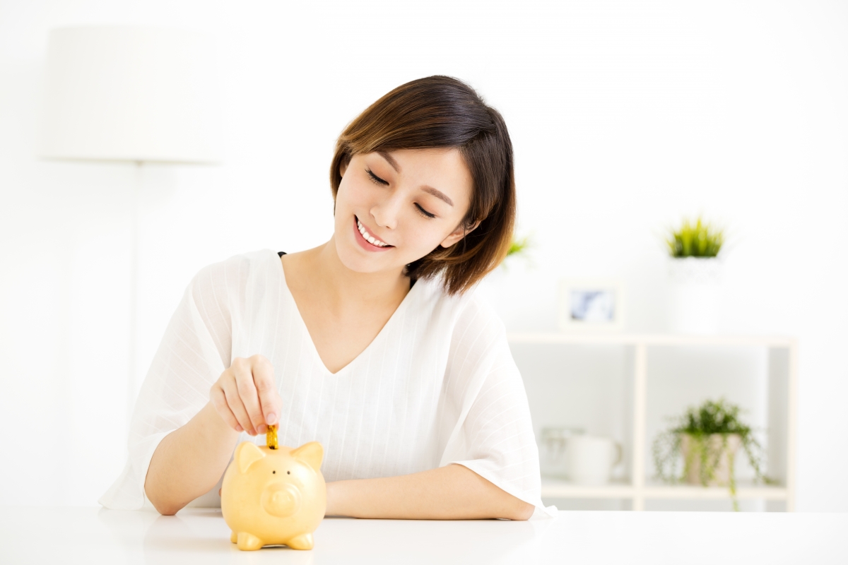 Lady putting coin into piggy bank