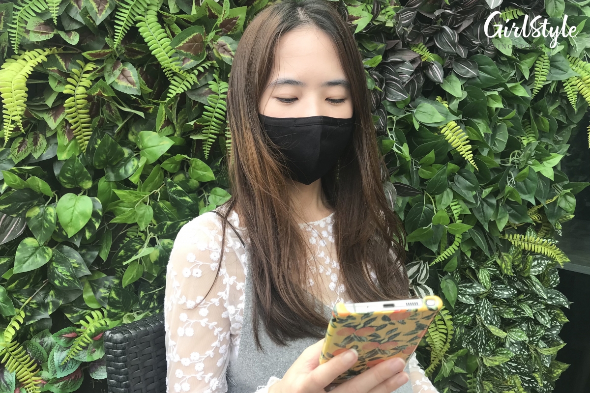asian woman wearing black face mask using phone