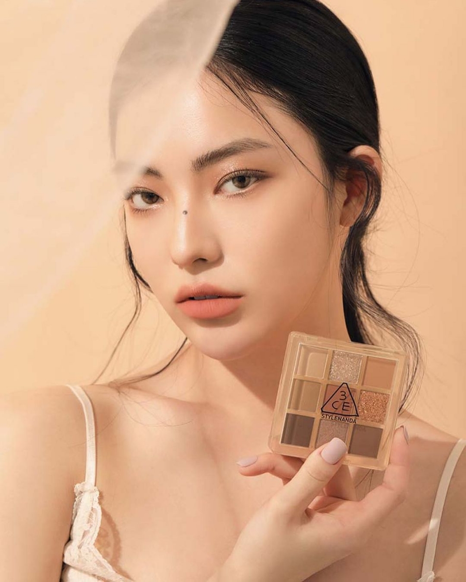 Model holding 3CE eyeshadow palette in Butter Cream