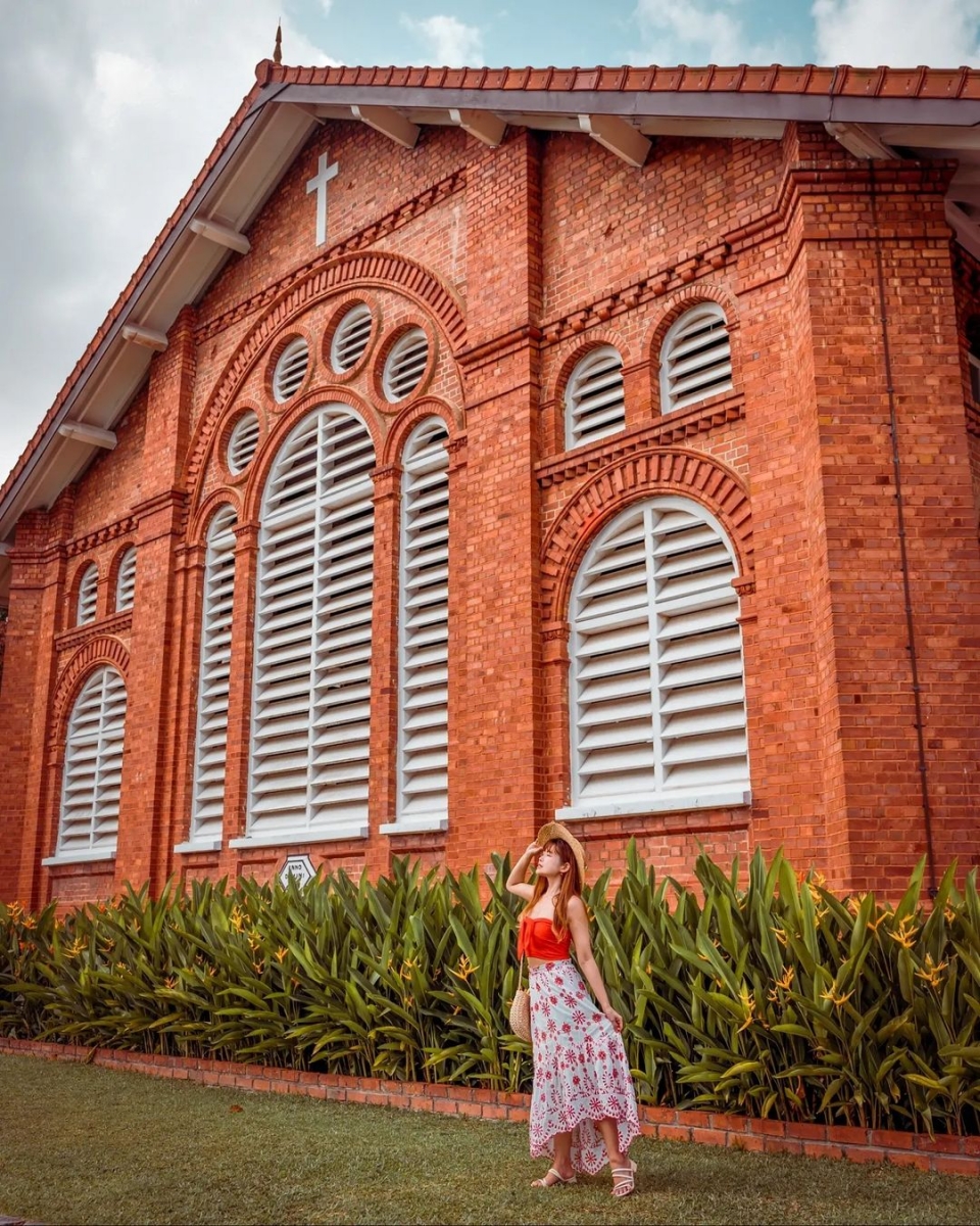 chervon khoo standing in front of red brick and white windows of saint george church singapore