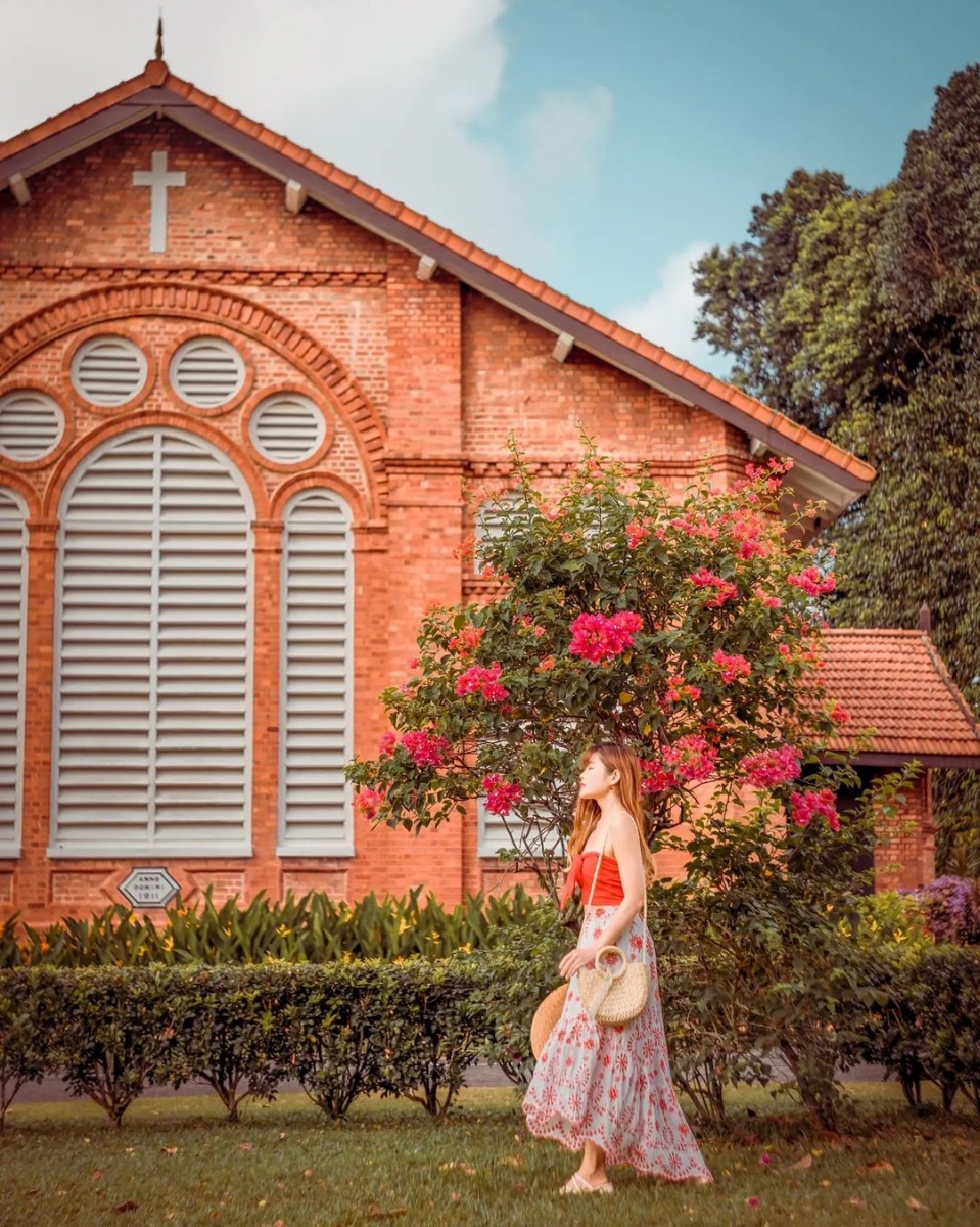 chervon khoo standing in front of flowering tree at saint george church singapore