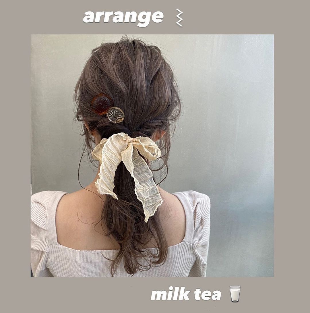 japanese hairstyle low voluminous ponytail with faux french braid twists and large beige ribbon accessory