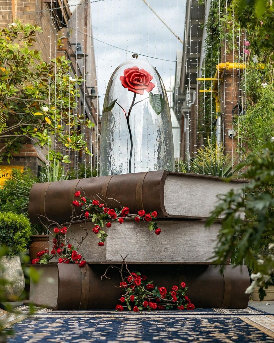 Giant books and enchanted rose display at Beauty and the Beast-themed cafe The Grounds of Alexandria