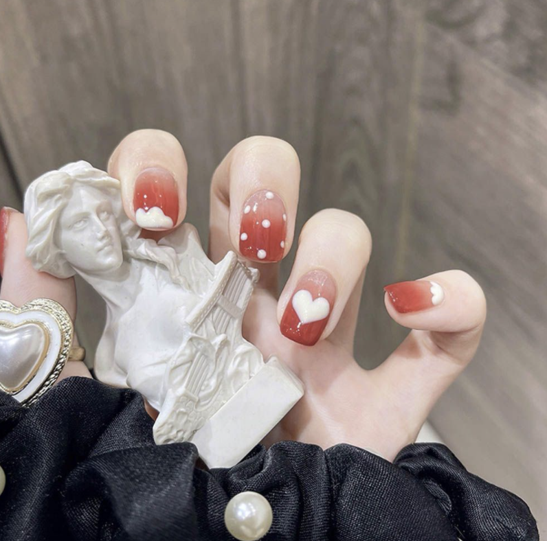 Red gradient nails with heart and polka dot motifs